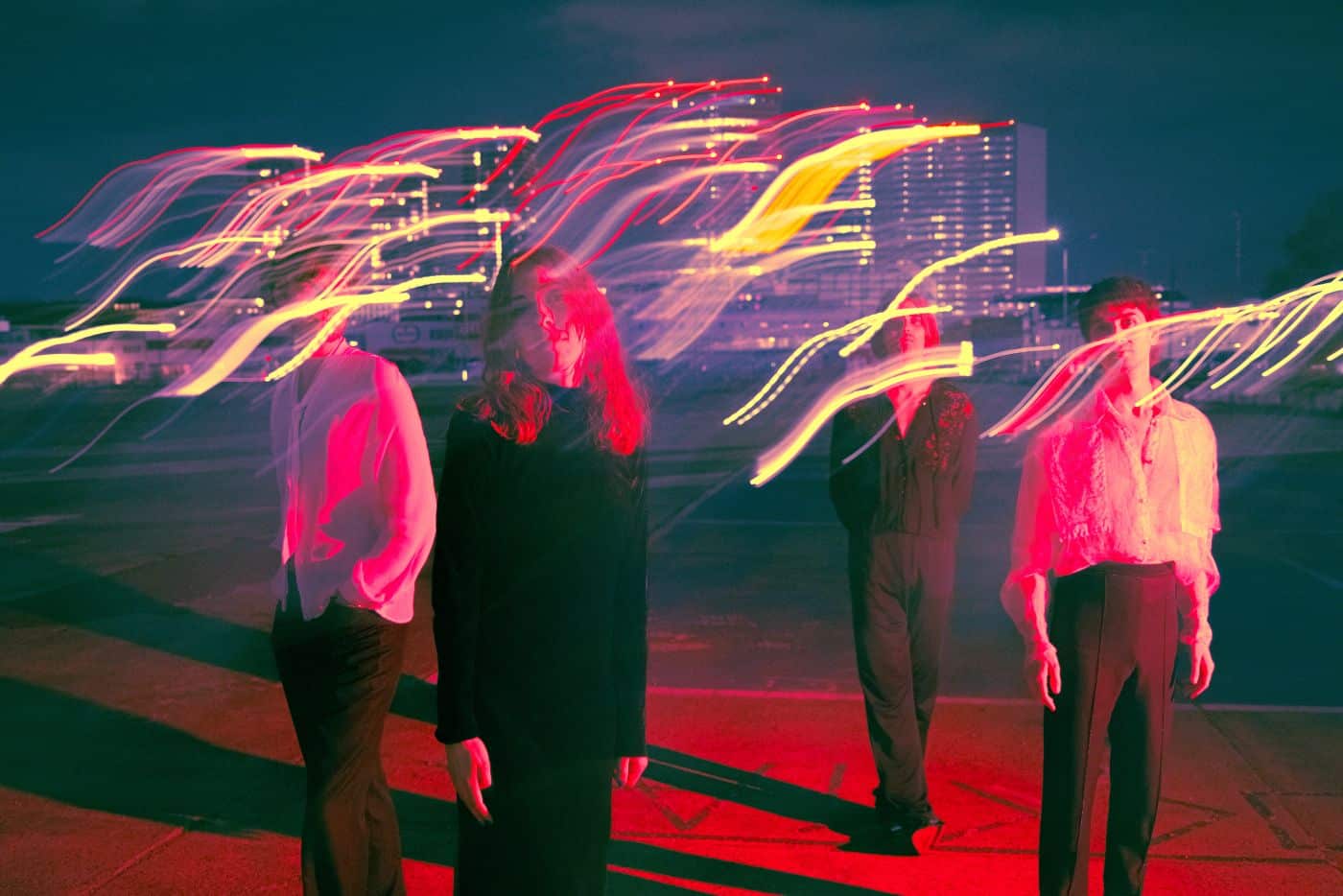 Bild der Band Die Wallners auf Platz vor Hochhäusern in rotem Licht beleuchtet