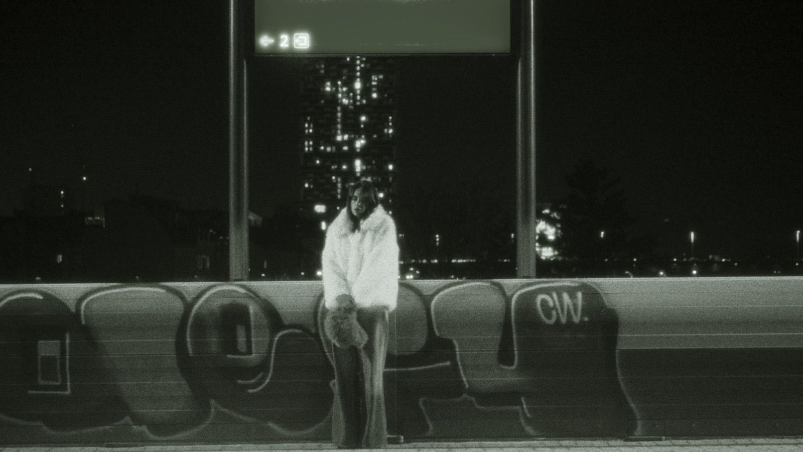 Ein schwarz-weiß Bild der Sängerin Diemarcha auf einem Bahnsteig in Wien.
