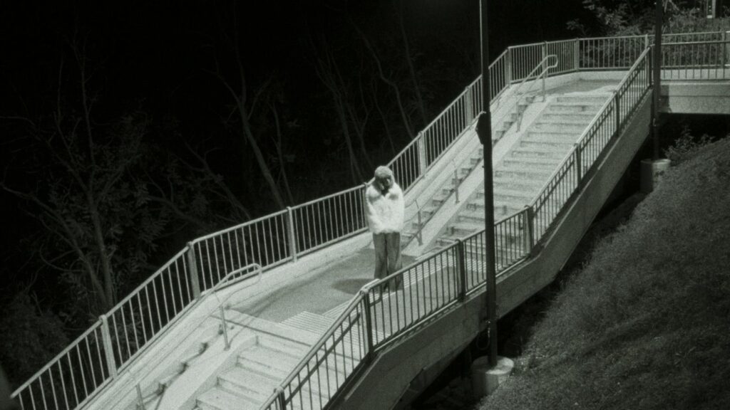 Ein Schwarz-Weiß Bild der Musikerin Diemarcha auf einer großen Stiege in der Nacht.
