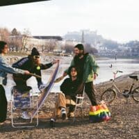 Die vierköpfige Band Flirtmachine am Ufer der Salzach, im Hintergrund die Stadt Salzburg und die Festung Hohensalzburg