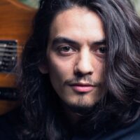 Bild des Musiker Kenji herbert mit Gitarre auf der Schulter