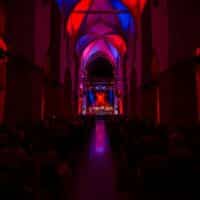 Bild des Innenraumes der Minoritenkirche während eines Konzertes, im roten Licht erleuchtet, von hinten fotografiert