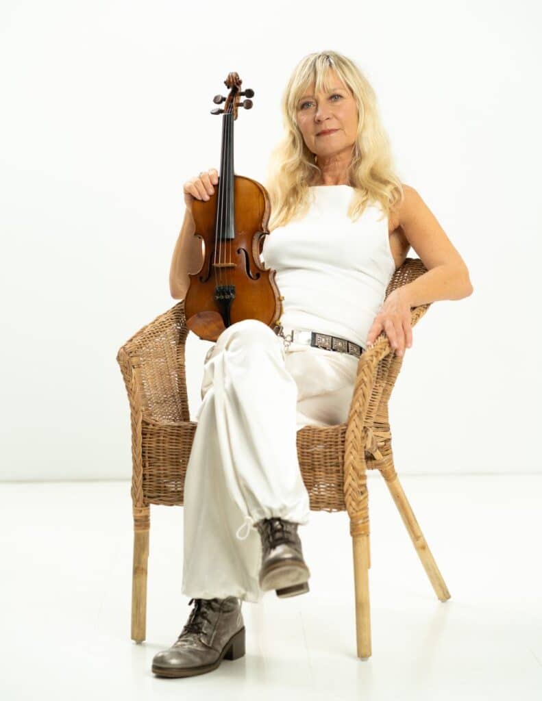 Bild der Musikerin Lena Willemark in einem Korbsessel sitzend mit der Geige am Schoß vor weißem Huntergrund