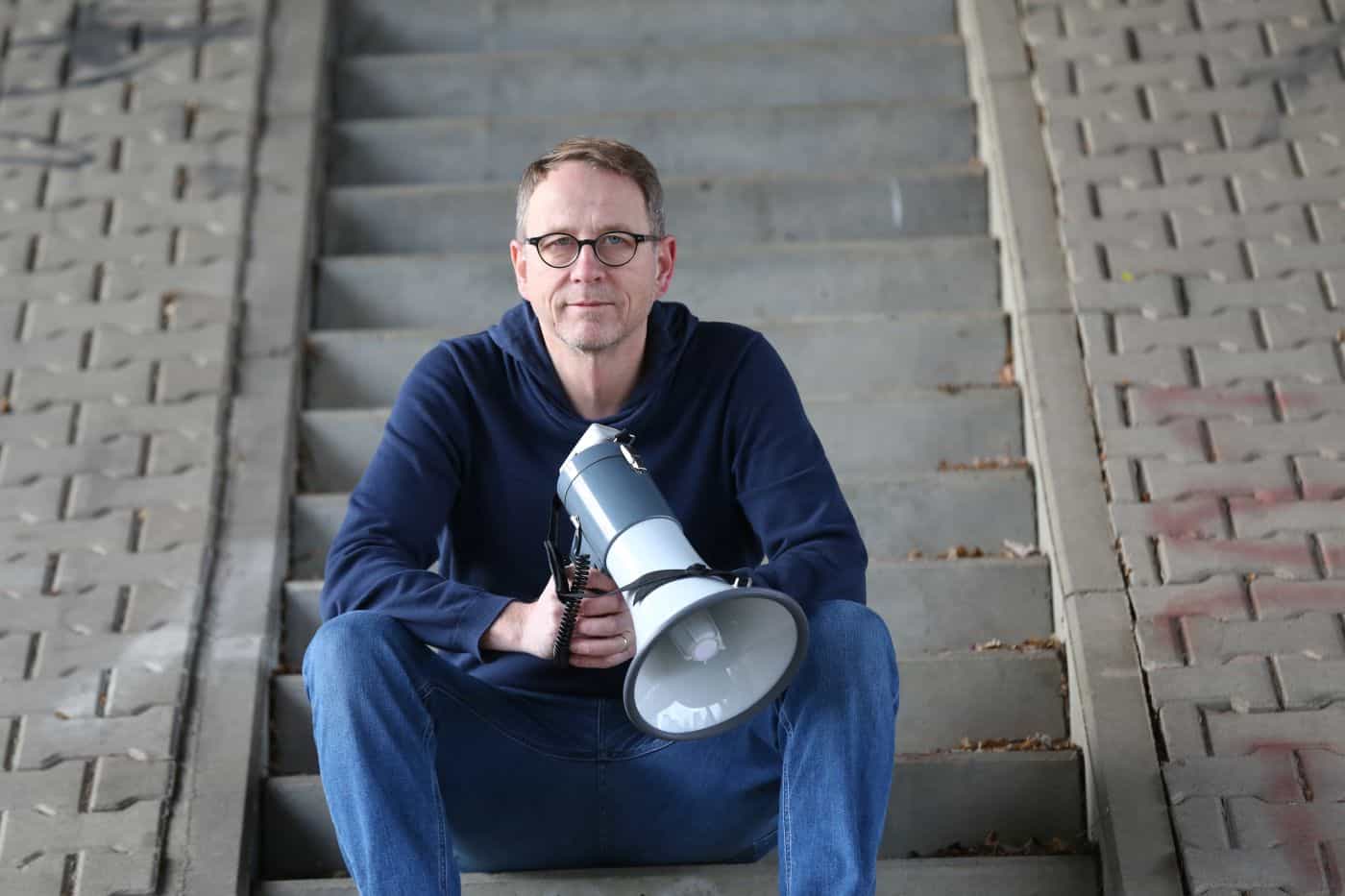 Bild Michael-Behrendt_sitzend-Stufen-Megaphon