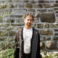 Der Sänger Philipp Spiegl steht vor einer Steinmauer