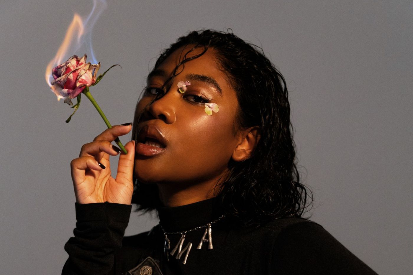 Ein Bild der Sängerin Rose May Alaba mit einer brennenden Rose in der Hand