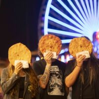 Bandfoto der Wiener Band Speck, Mitglieder halten Langos vor ihren Geichtern