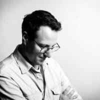 Schwarzweiß Bild des Musikers Simon Oberleitner mit hellem Hemd und Arme verschränkt
