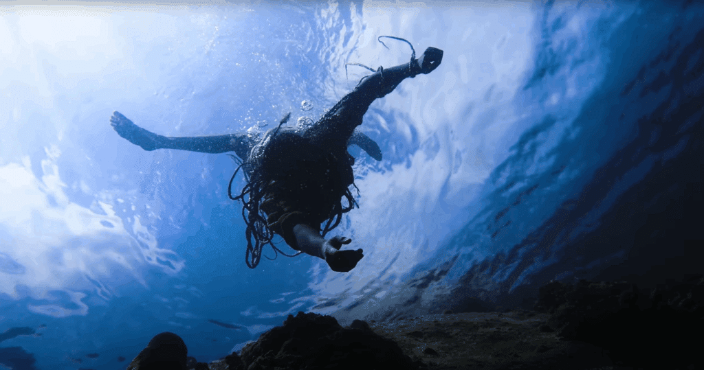 Videostill aus "Sound of the Waves". Die Sängerin Nee-Sha taucht gerade ins Wasser ein.