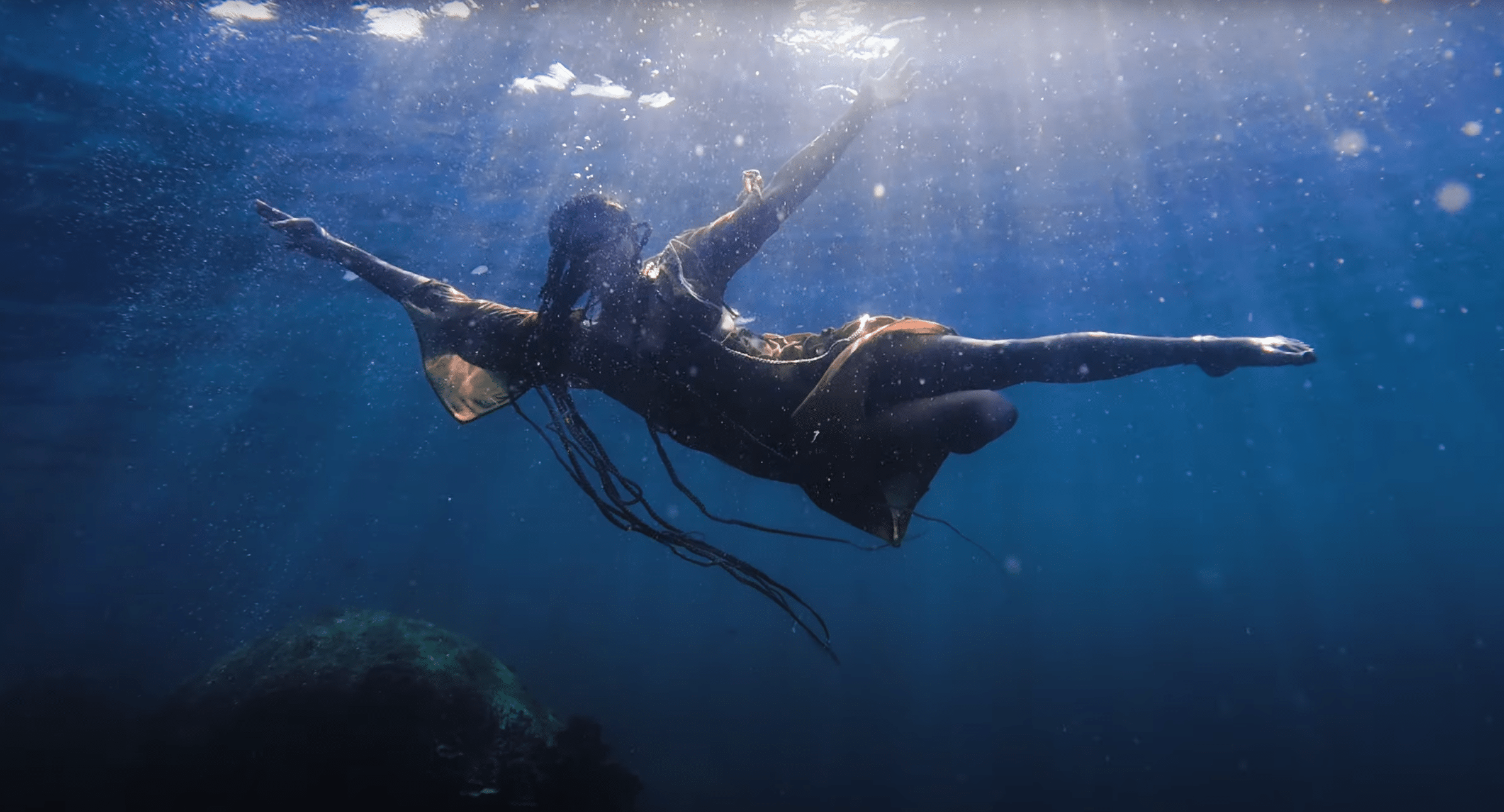 Videostill aus "Sound of the Waves". Die Sängerin Nee-Sha ist unter Wasser zu sehen.