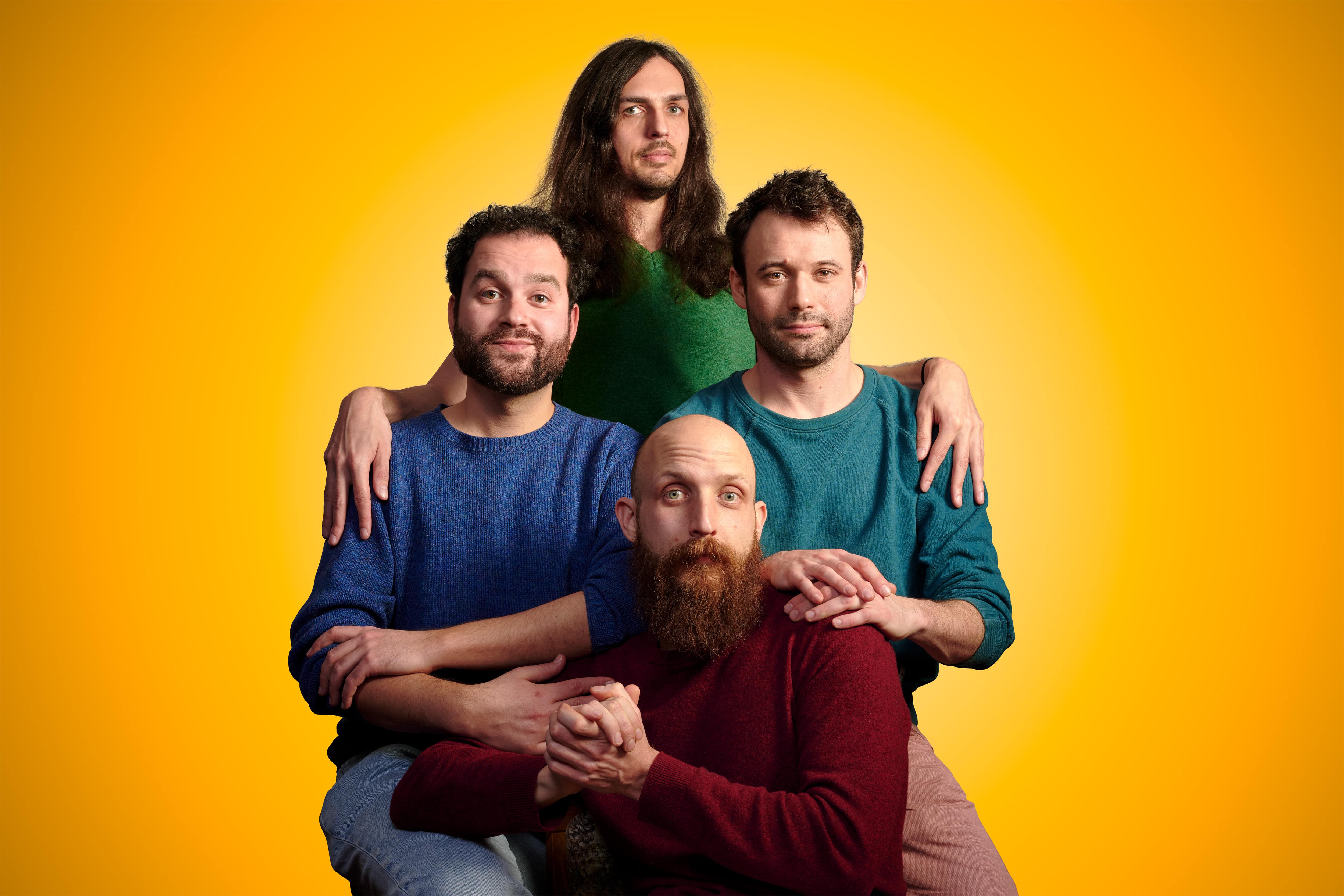 Die vierköpfige Band ZAPP GALURA vor einem gelben Hintergrund.