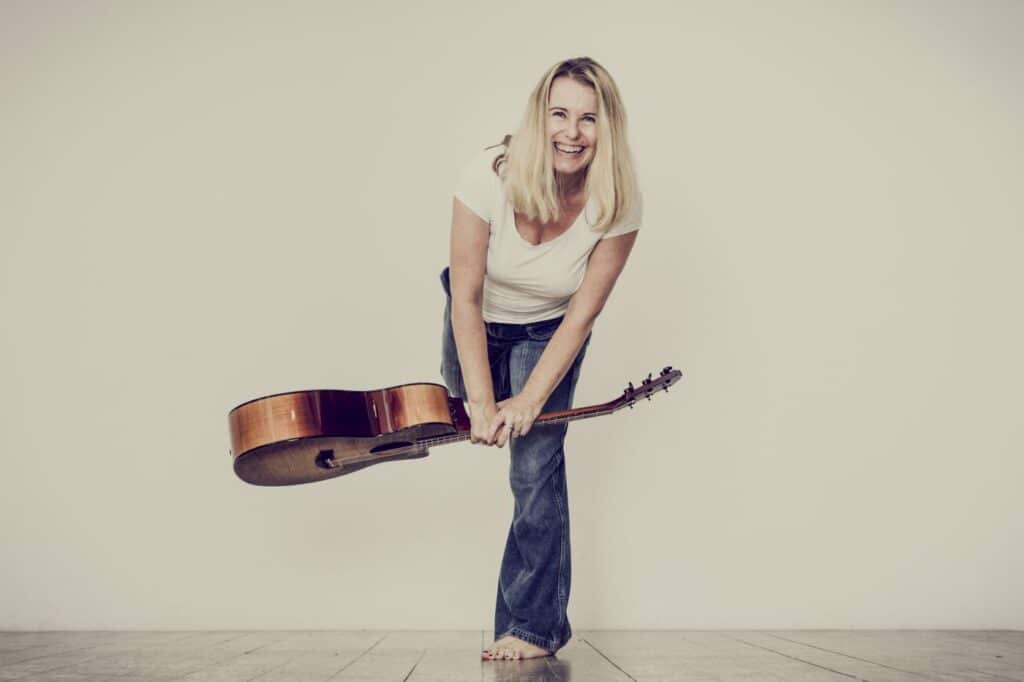Bild der Musikerin simon.loves.music mit Gitarre vor weißem Hintergrund