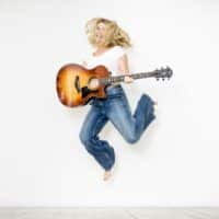 Bild der Musikerin simon_loves_music Mit Gitarre vor weißem Hintergrund springend