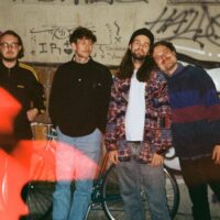 Die vierköpfige Band wolpertinger. in der Nacht vor einer Wand voller Graffiti